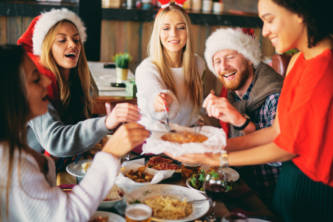 Friends wearing Santa hats sharing a meal at a table