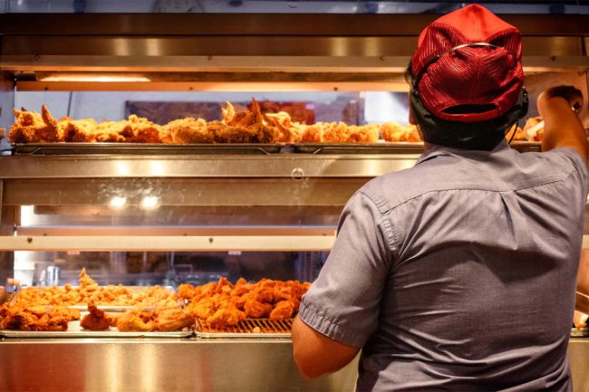 Foodservice worker handling fried chicken