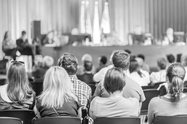 Black and white photo of people sitting in chairs for a meeting