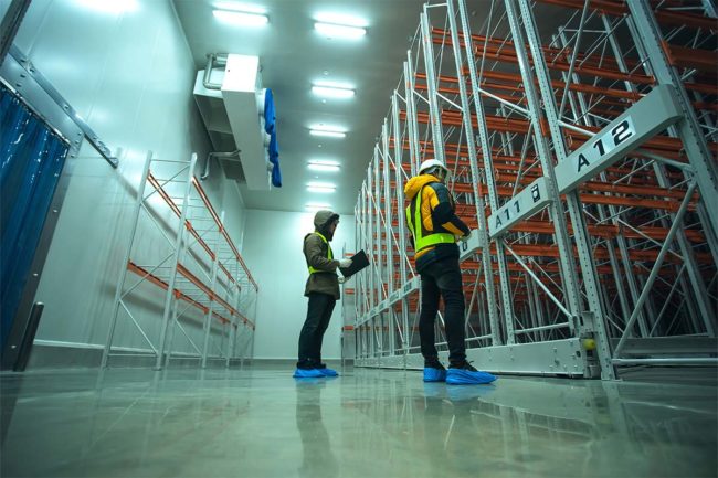 Two technician inspectors check machine shelf in cold warehouse