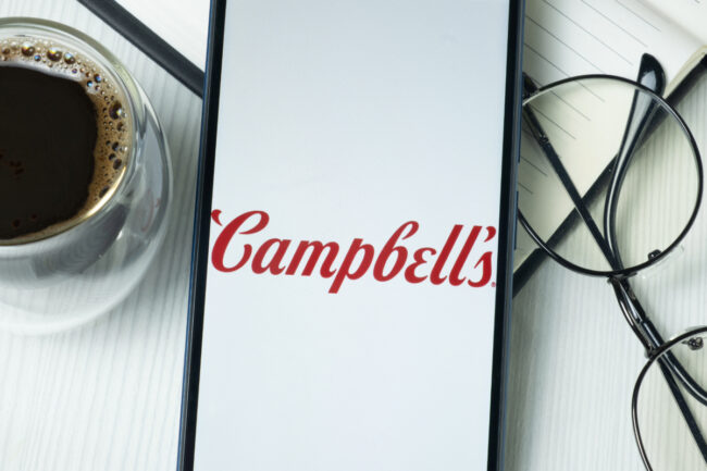 Campbell's logo on phone next to glasses and coffee cup