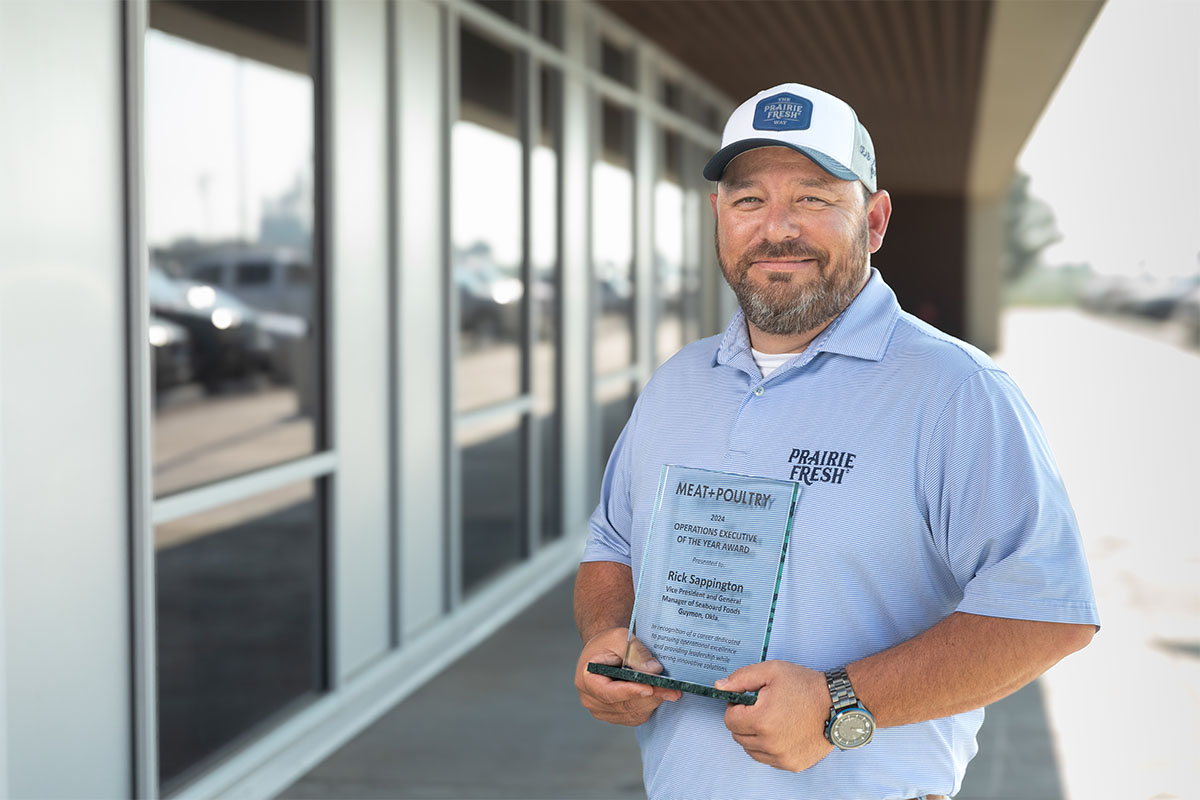 Rick Sappington hold Ops Exec of the Year award outside Seaboard Foods facility