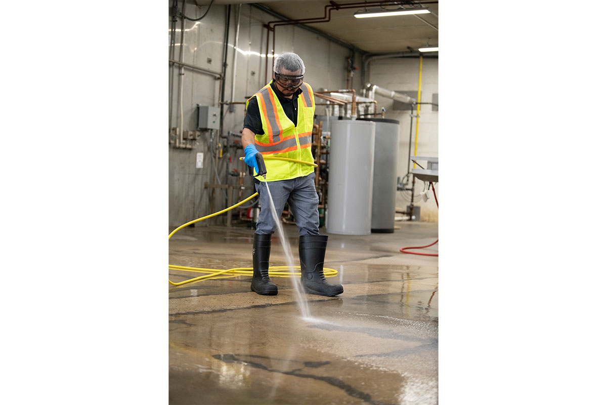 Worker cleans floor of a processing plant