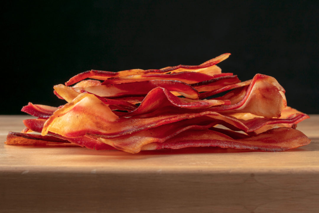 Close-up of a 3-layered club sandwich with bacon, tomato slices and salad,  on a wooden table, blurred garden background, 8k, high resolution,  professional food photography on Craiyon